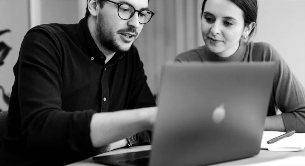 Homme et femme travaillant sur un site web devant un ordinateur.